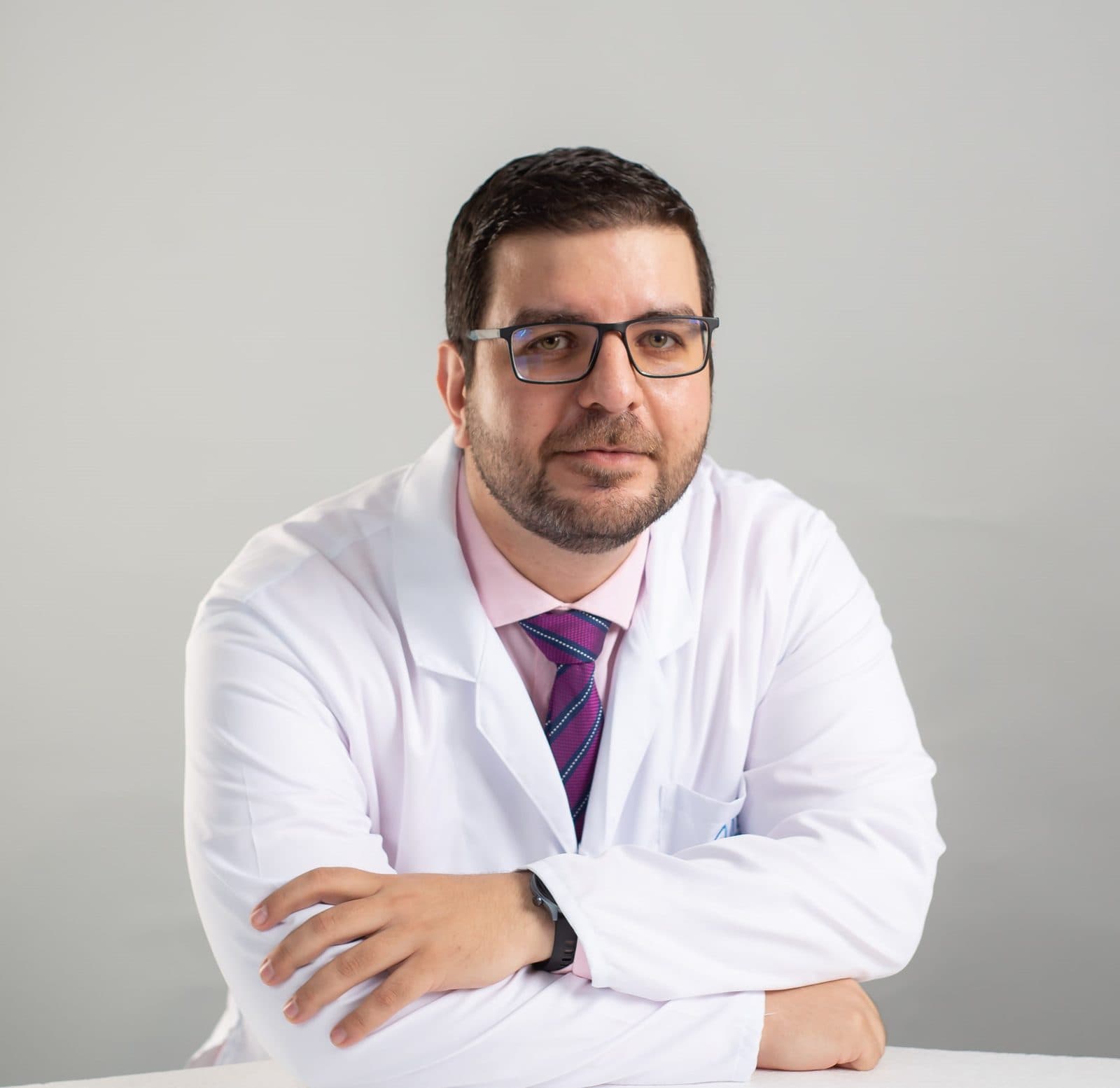 El Dr. Osama Bahsas Zaky con bata blanca, mirando a la cámara con los brazos cruzados